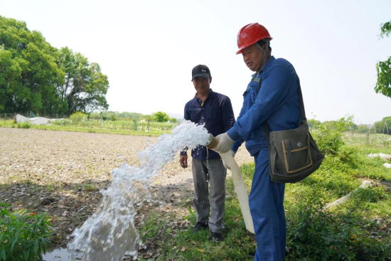 图为电力人员在田边上为农户装表接电抽水灌溉