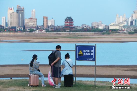 图为8月22日傍晚，游客拖着行李箱来到南昌赣江边欣赏江景，对岸是江南名楼滕王阁。 刘占昆 摄