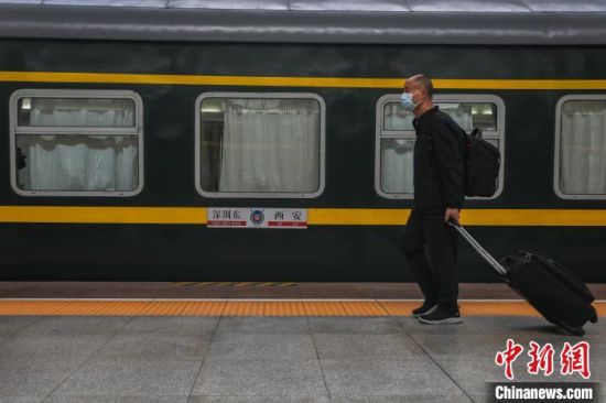 7图为一位旅客携带行李从一列火车旁走过。　刘力鑫 摄