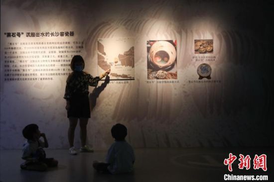 4图为一位家长在给两位小朋友讲解墙上展板的内容。　刘力鑫 摄