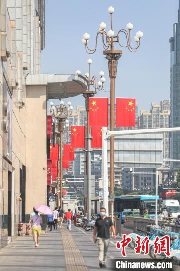 5 图为南昌城区街头悬挂着鲜艳的国旗，市民从国旗下走过。　刘力鑫 摄