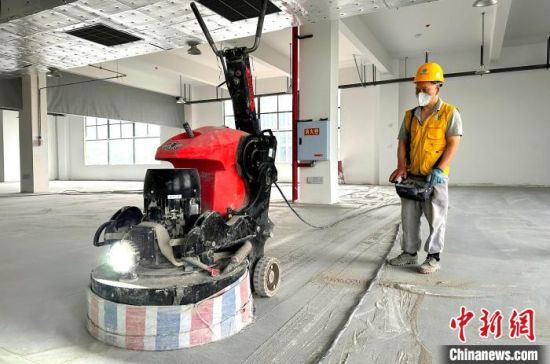图为一名工人正在浙江杭州转塘银泰城操控地坪研磨机器人进行基础研磨作业。　余干县委统战部供图