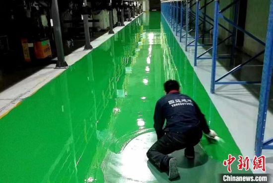 图为一名工人正在浙江凌博机械厂进行环氧地坪面层施工作业。　　余干县委统战部供图