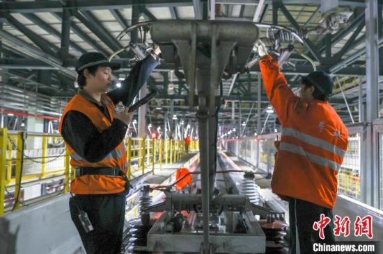 图为机械师在一辆动车组列车车顶检查受电弓状态。刘力鑫 摄