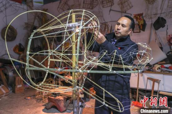 图为史克滨使用棉纸绳在扎龙头，这个龙头所属的龙灯全长约18米长，预计将在2024龙年春节前全部编扎好。刘力鑫 摄