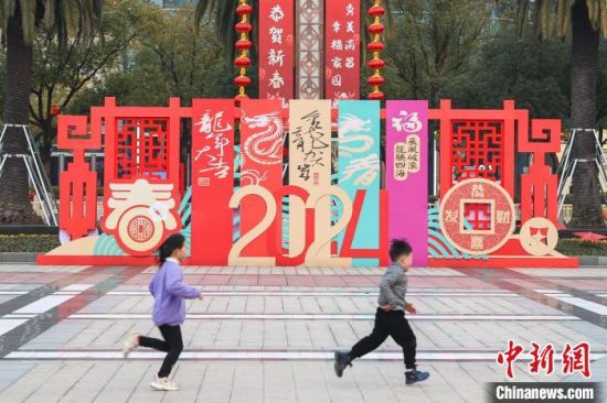 图为江西南昌八一广场，小朋友从龙年春节主题装饰前跑过。刘力鑫 摄