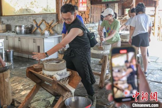 图为香港青年在体验用石磨磨豆浆。刘力鑫 摄
